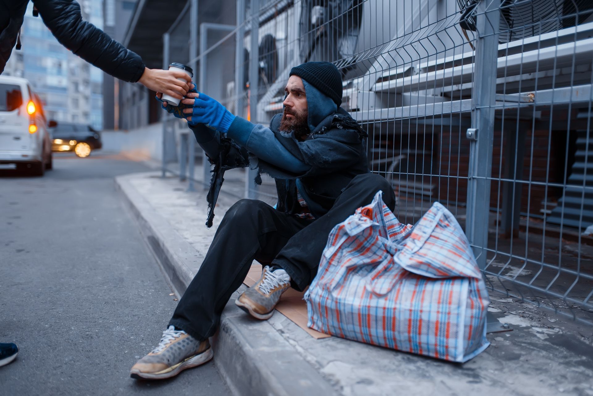 Person gives hot coffee to homeless